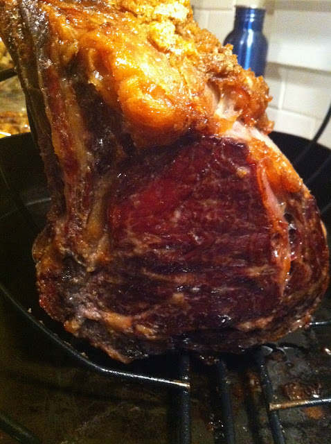 Large roasted meat joint with charred crust and pink interior resting on a rack, warm kitchen background